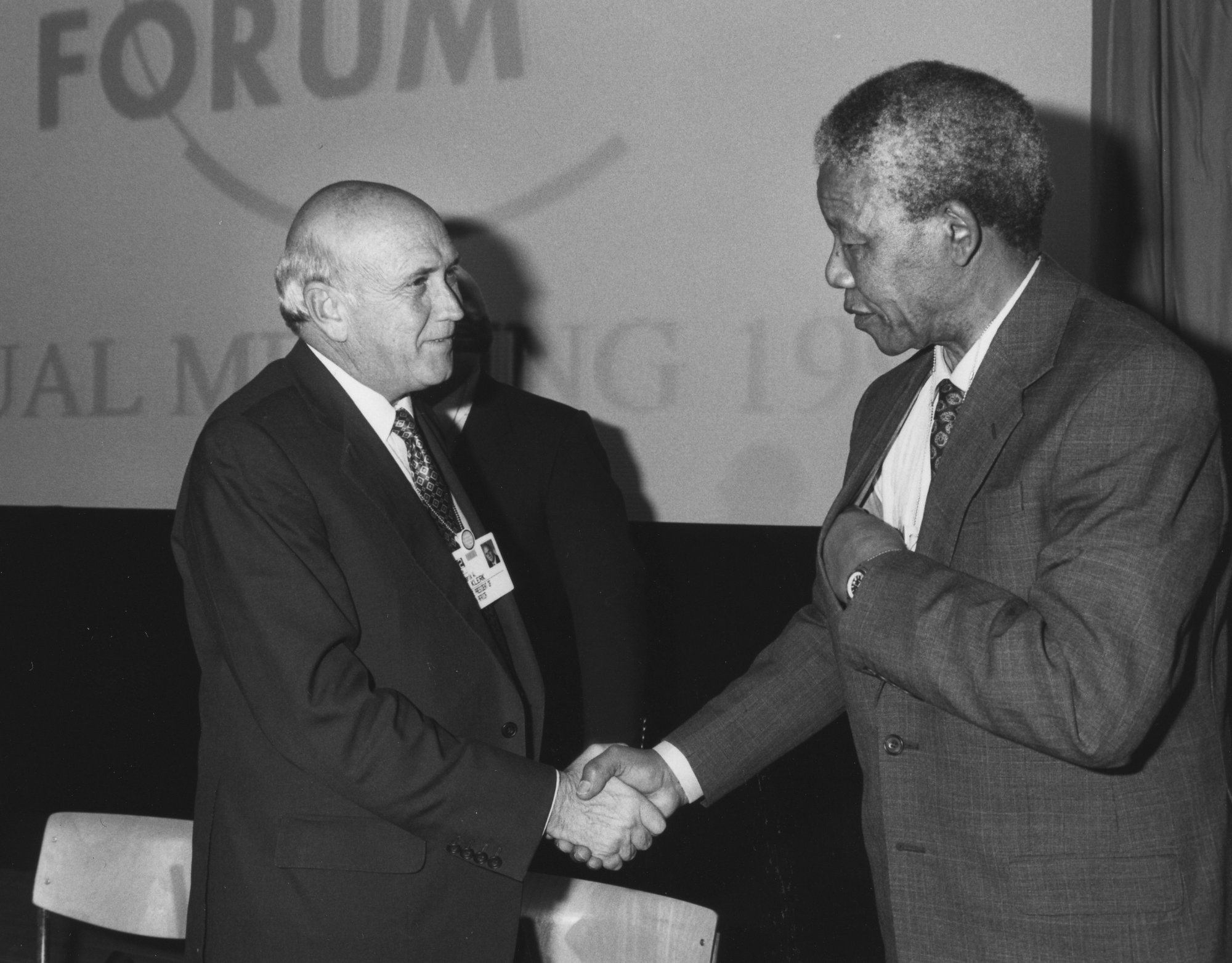 F. W. de Klerk and Nelson Mandela shake hands on a conference stage at the World Economic Forum in Davos, 1992